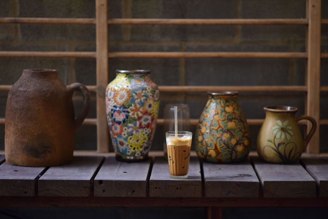 Iced coffee shared on a wooden bench beside handcrafted ceramics