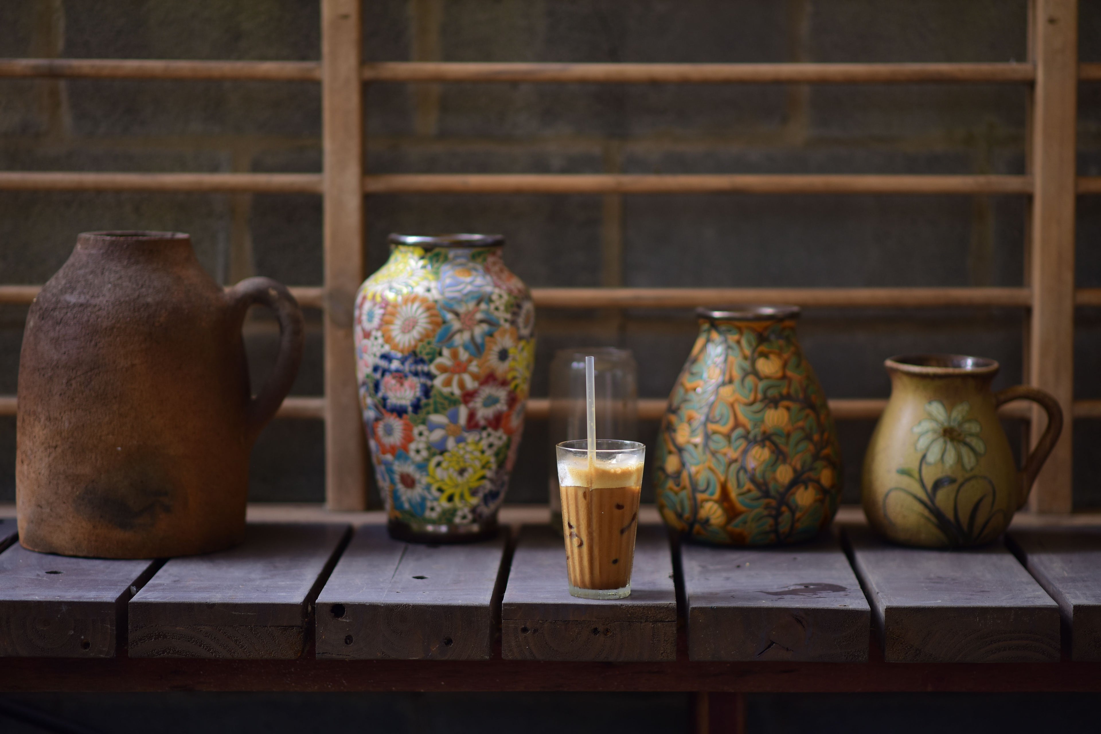 Iced coffee shared on a wooden bench beside handcrafted ceramics