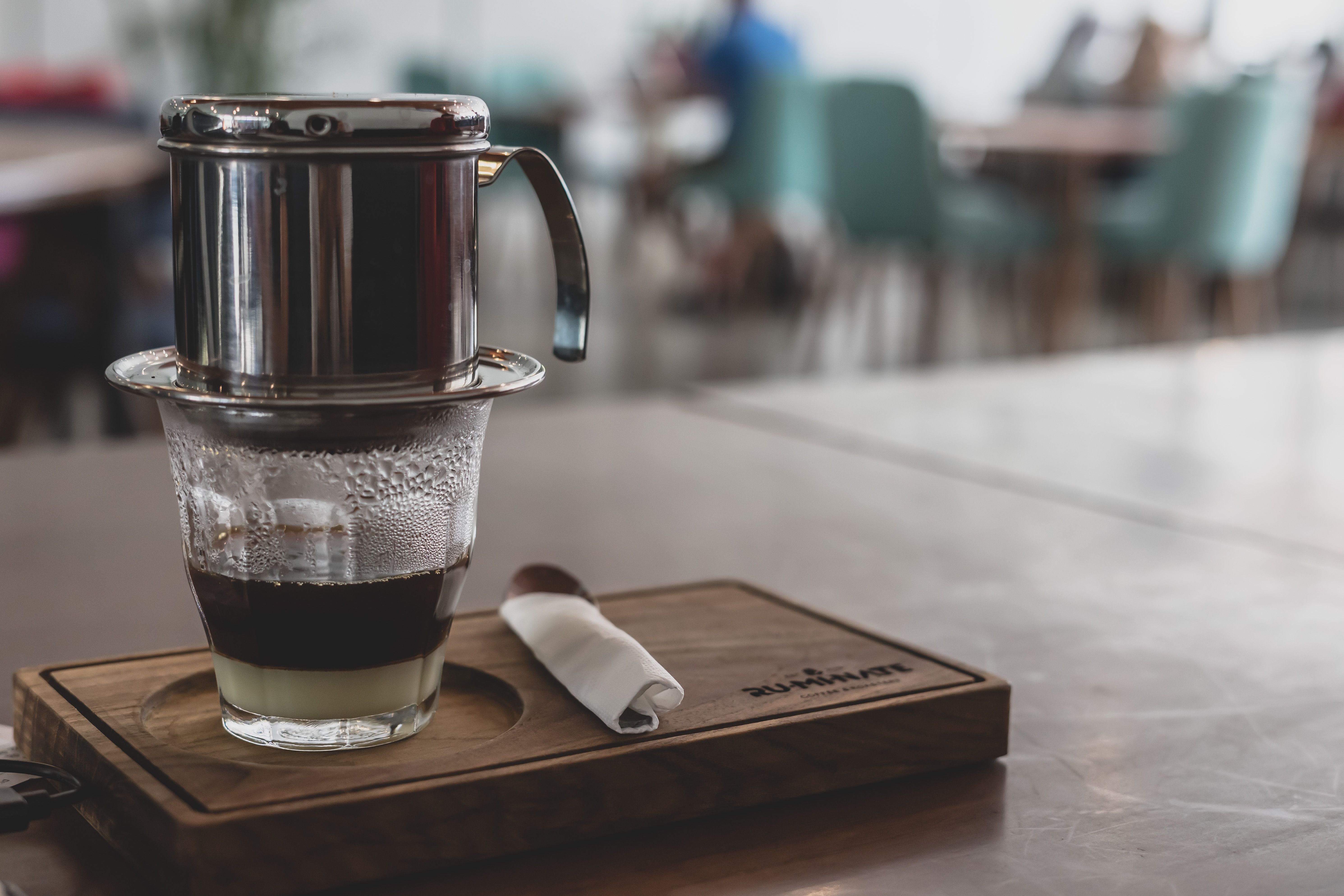 Vietnamese phin filter brewing slowly over a glass in a café
